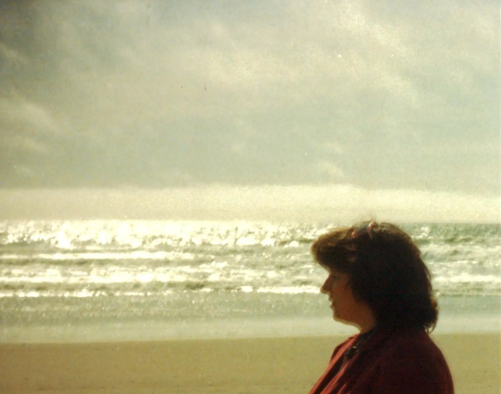 Person standing by a sunlit beach.