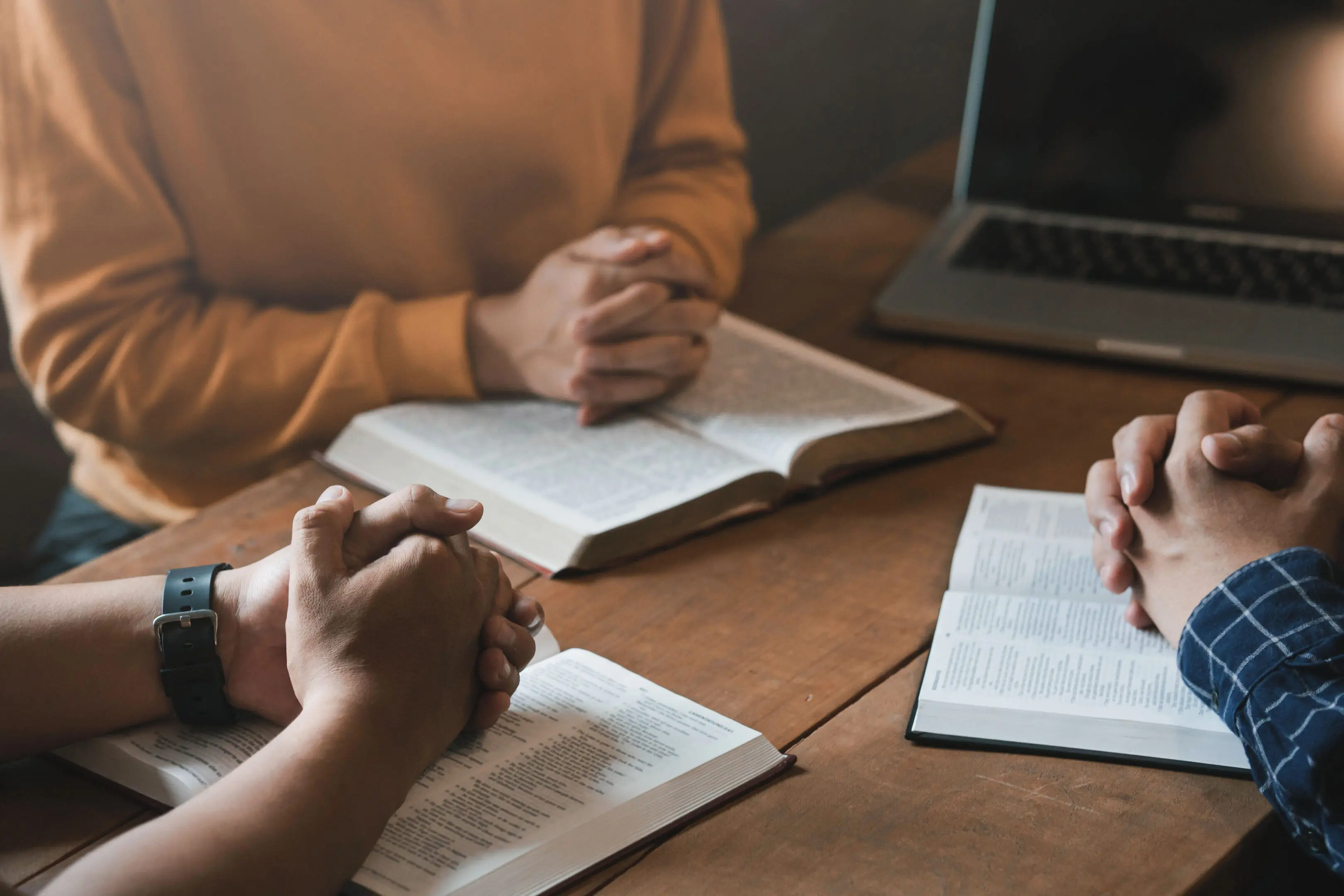 People praying with open books on table.